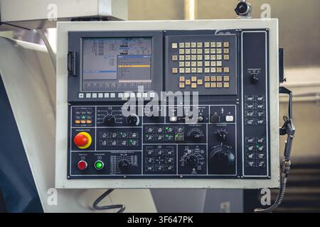 Control panel of modern CNC machine with display screen showing code, buttons and emergency stop switch in industrial factory Stock Photo