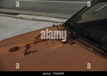 Close up of an old car hood with peeling paint and heavy rust corrosion. Weathered vehicle surface showing oxidation and deterioration. Stock Photo