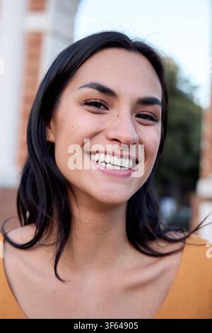 Happy young latin woman smiling outdoors in urban setting Stock Photo
