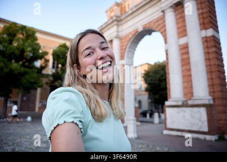 Young woman smiling in front of a brick archway Stock Photo