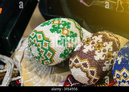Intricately beaded spheres in vibrant colors and patterns, featuring detailed beadwork, geometric and abstract designs, on a wooden surface, with warm Stock Photo
