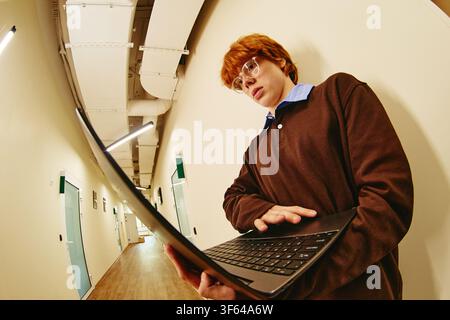 Man Using Laptop in Office Corridor for Digital Learning Stock Photo