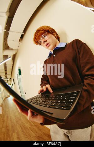 Man Using Laptop in Modern Office Corridor Stock Photo