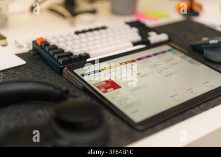 Tablet Display Agile Kanban Board Software Development Workspace. Modern office desk setup featuring a digital tablet showing project management task Stock Photo