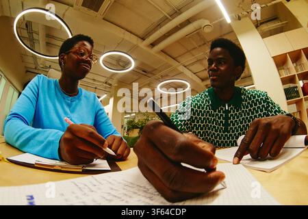 Black Man and Black Woman Working Together in Modern Library Stock Photo