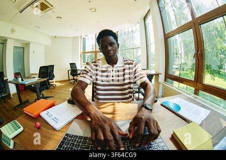 Portrait of Black Man Working on Laptop in Modern Office Stock Photo