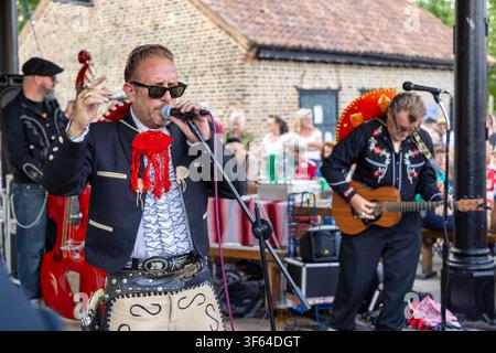 Carlos and the Banditos performing at Rockin’ at the Mills, with the singer looking to the right holding the microphone, embroidered Mexican‑style Stock Photo