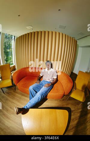 Black Man Relaxing on Sofa in Modern Creative Office Lobby Stock Photo