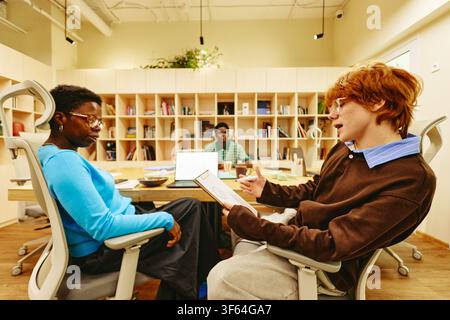 Diverse Colleagues Discussing Project Details in Modern Office Stock Photo