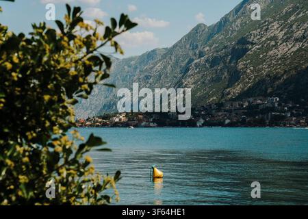 Rocky mountain coastline reflected in the calm waters of the Bay of Kotor. Peaceful summer landscape on Montenegro's Adriatic coast. Stock Photo