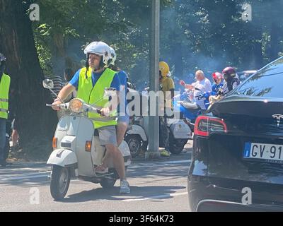 Castellarquato, Italy July 8th 2026 Riders in high visibility vests on classic Vespa scooters traveling through a street during a rally event Stock Photo