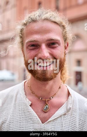 Portrait of attractive smiling young man looking at camera in park. Caucasian male handsome model. Stock Photo