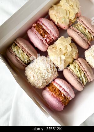 Overhead view of assorted French macarons set in a white gift box with various toppings Stock Photo