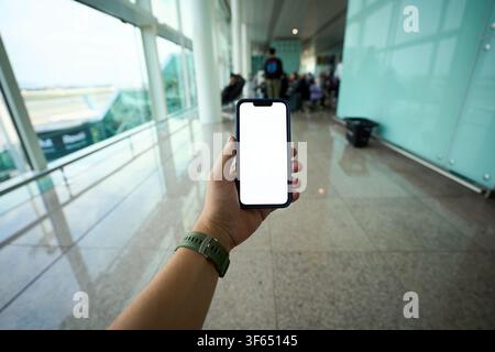 Hand holding smartphone with blank screen at airport. Stock Photo