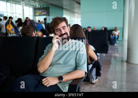Happy man talking on smartphone in airport lounge. Stock Photo