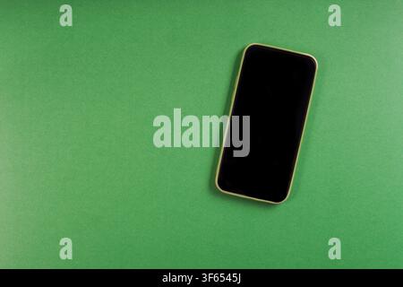 mobile phone or smartphone with blank screen on green background with copy space Stock Photo