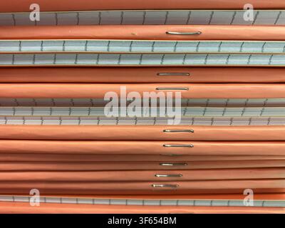 Close-up view of thick orange notebooks stacked neatly, featuring metal staples and lined pages, ideal for educational or office use Stock Photo