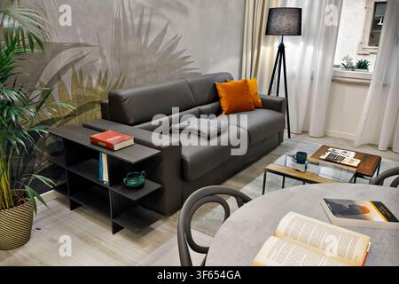 Contemporary apartment in Turin, Italy, converted from office to residential use, with leather sofa, floral wallpaper, dining table and window Stock Photo