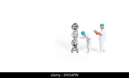 Miniature figures of medical scientists in protective suits examining a silver DNA double helix model, isolated on a white background. Concept of gene Stock Photo