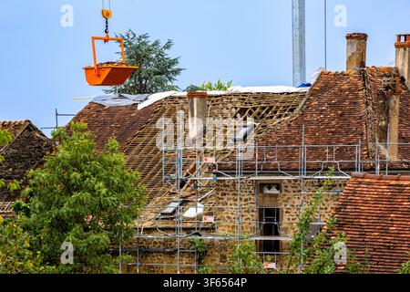 Dijon Burgundy France June 6 2026. Two construction workers using a crane with a special tray to disassemble and collect old ceramic roof tiles during Stock Photo