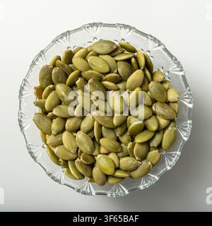 Pumpkin seeds in glass bowl on white background Stock Photo
