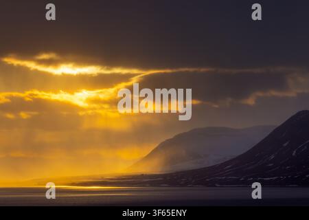 Isfjorden / Isfjord showing midnight sun at sunset with dark rain clouds in spring, Spitsbergen / Svalbard, Norway Stock Photo
