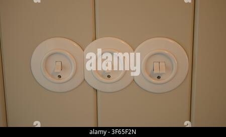 Three Round Vintage-Style White Toggle Light Switches on a Cream Panelled Wall — Home Electrics, Retro Interior Detail and Energy Saving Concept Stock Photo