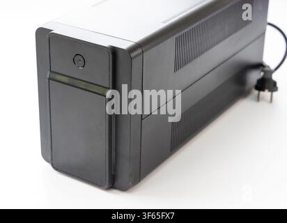 A black uninterruptible power supply unit stands isolated against a clean white background Stock Photo