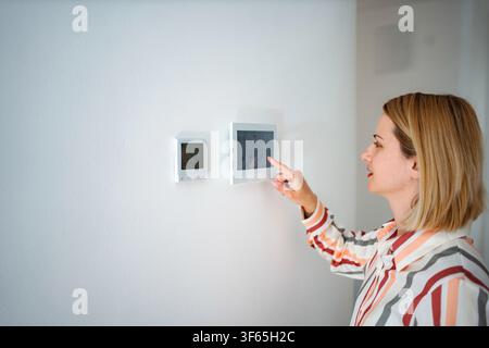 Woman adjusting smart home thermostat control panel Stock Photo