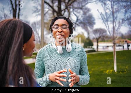 Two young adult women having a conversation in a park setting Stock Photo