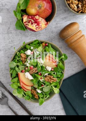 Overhead view of fresh arugula salad with feta cheese apple slices walnuts and pomegranate seeds on a light background Stock Photo