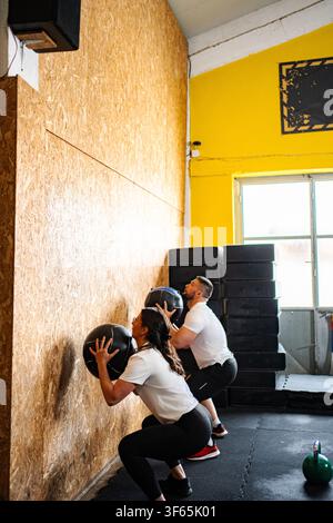 Couple doing wall ball exercise in crossfit gym Stock Photo