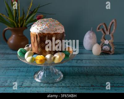 Freshly baked traditional Easter bread served with decorated eggs and spring flowers on a rustic wooden table Stock Photo