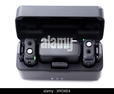 A wireless microphone charging case is open on a white background, revealing two transmitters and a receiver inside Stock Photo