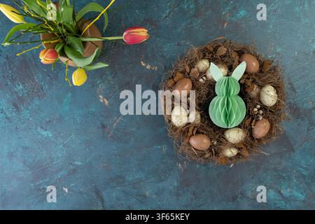 Colorful hand decorated Easter eggs arranged in a rustic wooden crate with spring flowers on a wooden table Stock Photo
