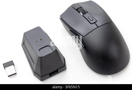 A wireless computer mouse is displayed next to its charging dock and a USB receiver on a white surface Stock Photo