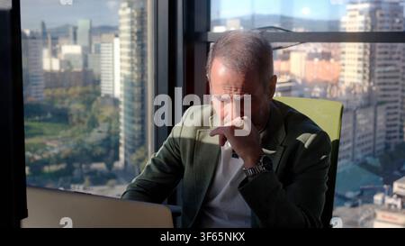 Stressed businessman thinking while working on laptop in modern office Stock Photo