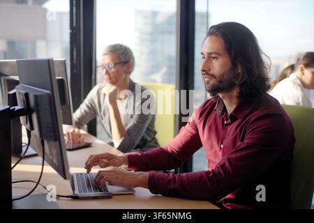 Focused businessman working on laptop in modern open office Stock Photo