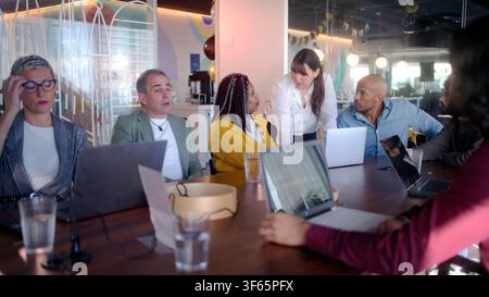 Business team analyzing data on laptops during meeting in modern office Stock Photo