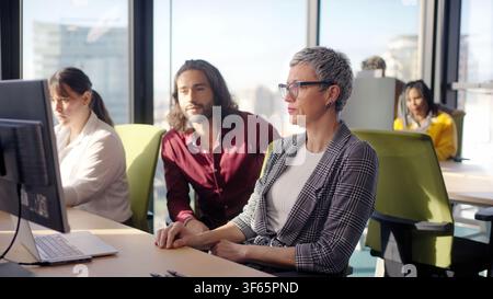 Mature businesswoman working with colleagues in modern open office Stock Photo
