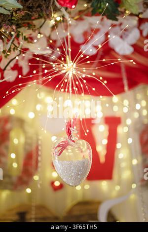 Unfocused shot of 14 February Valentines Day background. Shiny sparkling garland lights, flowers, hearts and bokeh.  Copy space. Stock Photo