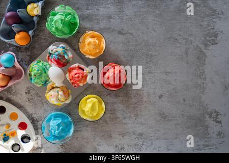 Freshly dyed Easter eggs resting in shaving foam on a gray tabletop during the marbling process for colorful Easter decorations Stock Photo