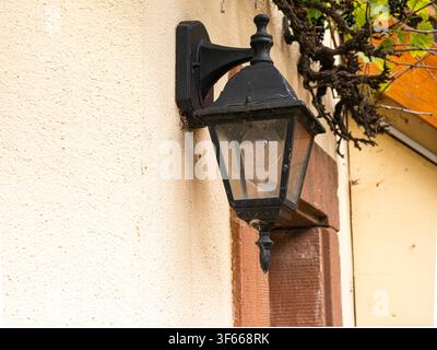 Black vintage street lantern mounted on a rustic building wall Stock Photo
