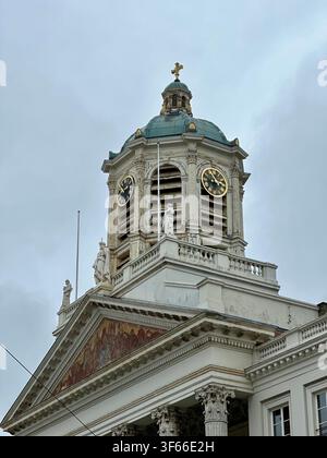 Historic church clock tower with statues and green dome. Close-up of a classical European church clock tower featuring ornate statues, golden clock fa Stock Photo