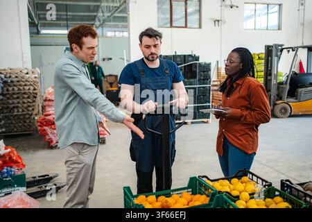 Warehouse workers discussing logistics and fresh fruit inventory Stock Photo
