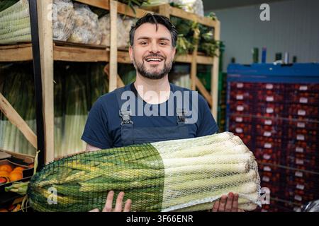 Smiling man handling fresh leeks in produce warehouse Stock Photo