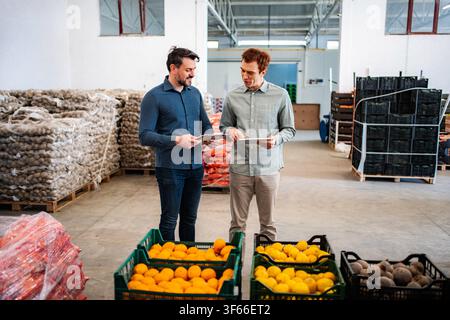 Two men discussing inventory in a fresh produce warehouse Stock Photo