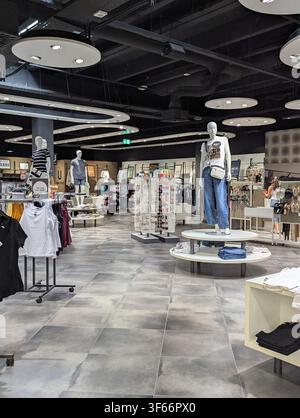 Modern clothing store interior with mannequins, denim jeans display, warm lights Stock Photo