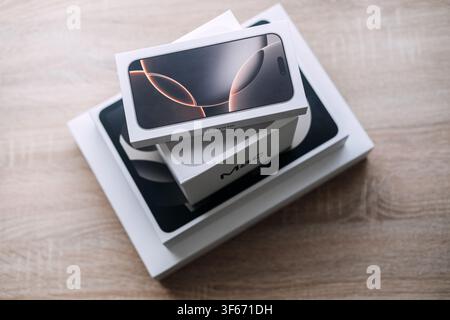 Apple boxes with iPhone and Mac labels stacked on table. Apple tech for productivity, digital lifestyle apple devices, modern workspace technology Stock Photo