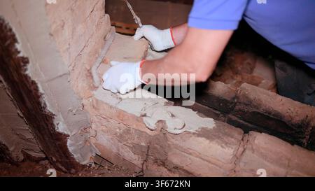 Construction worker restoring an old brick wall using mortar and trowel Stock Photo